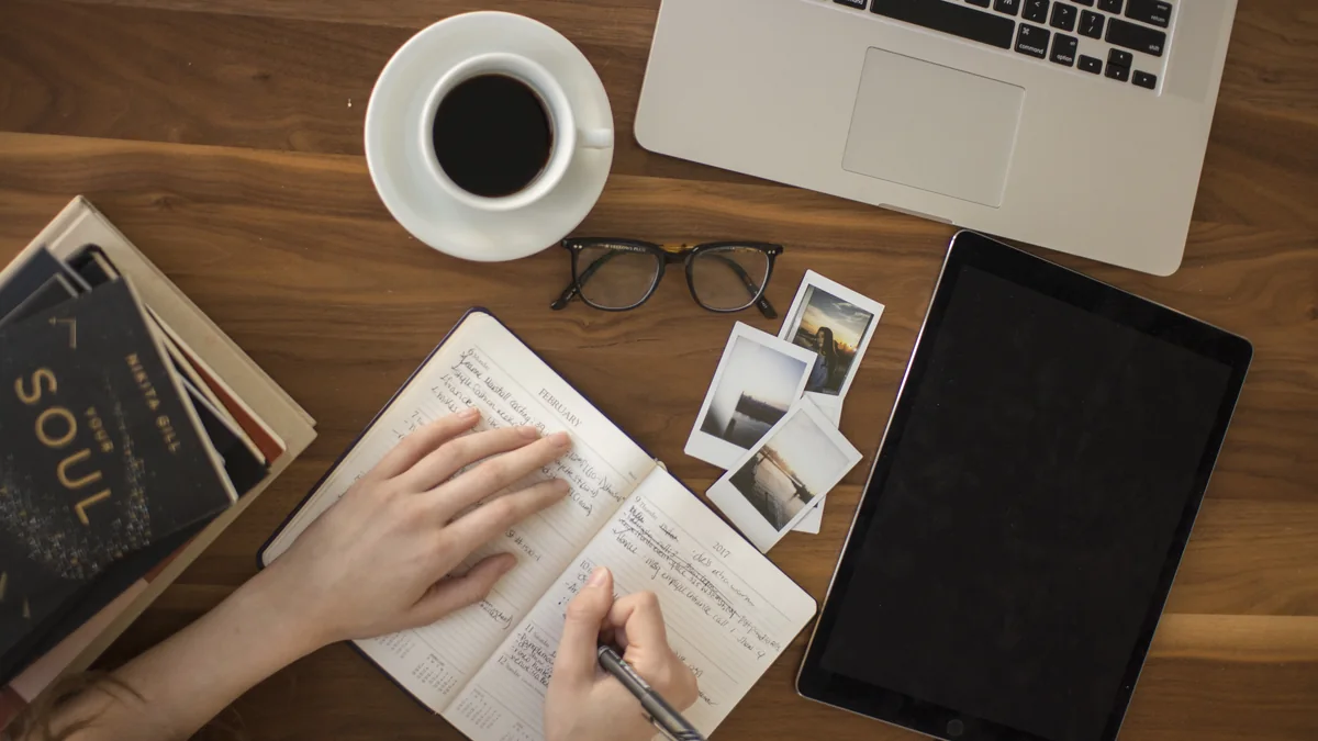 A journal, pen, and coffee on a morning table